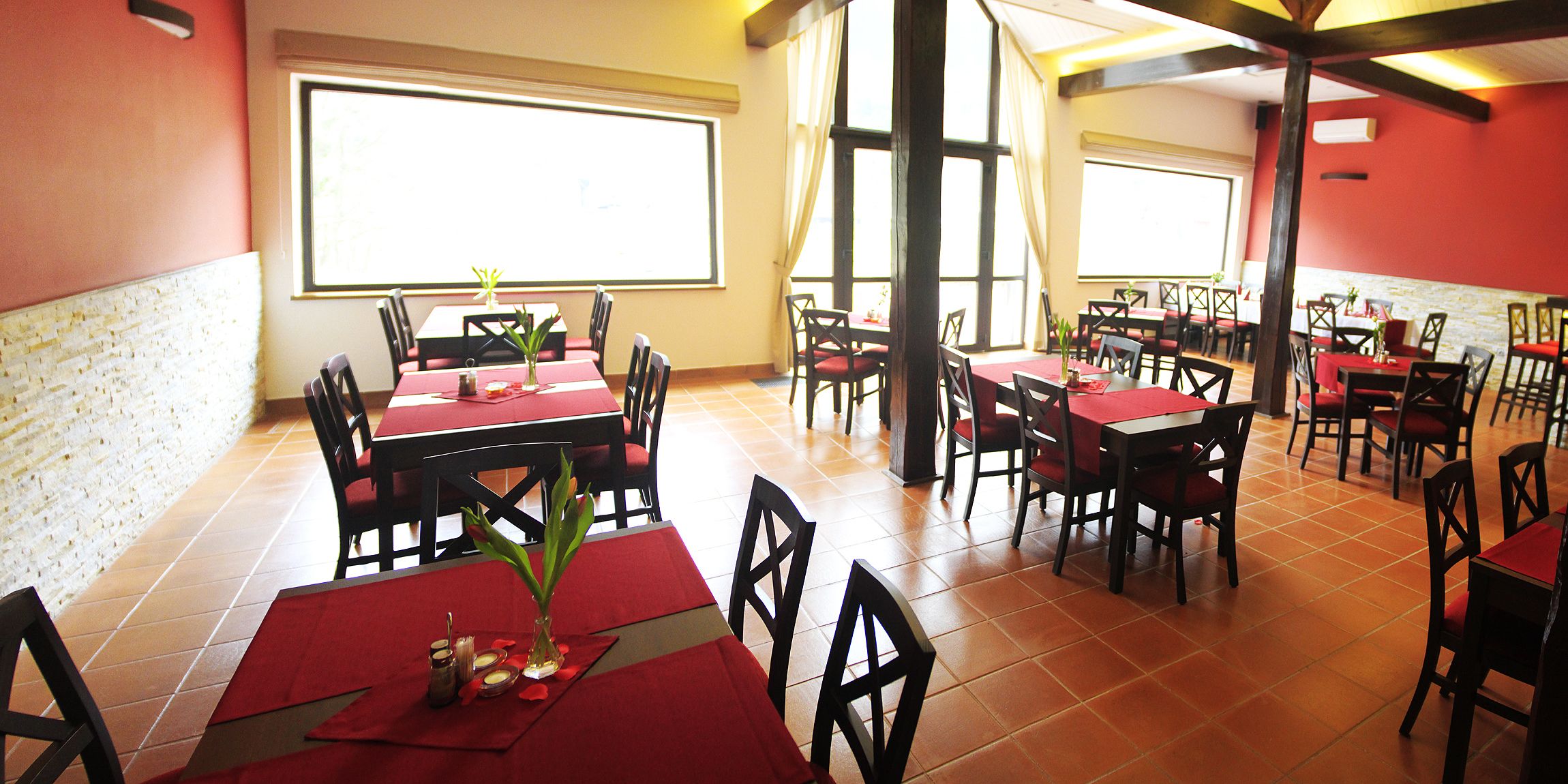 Un ristorante con diversi tavoli e sedie, ampie finestre e una parete in mattoni.
