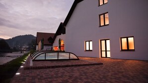 A modern building with a sloped roof, multiple windows, and a paved walkway. - Hotel Vír (Vir)