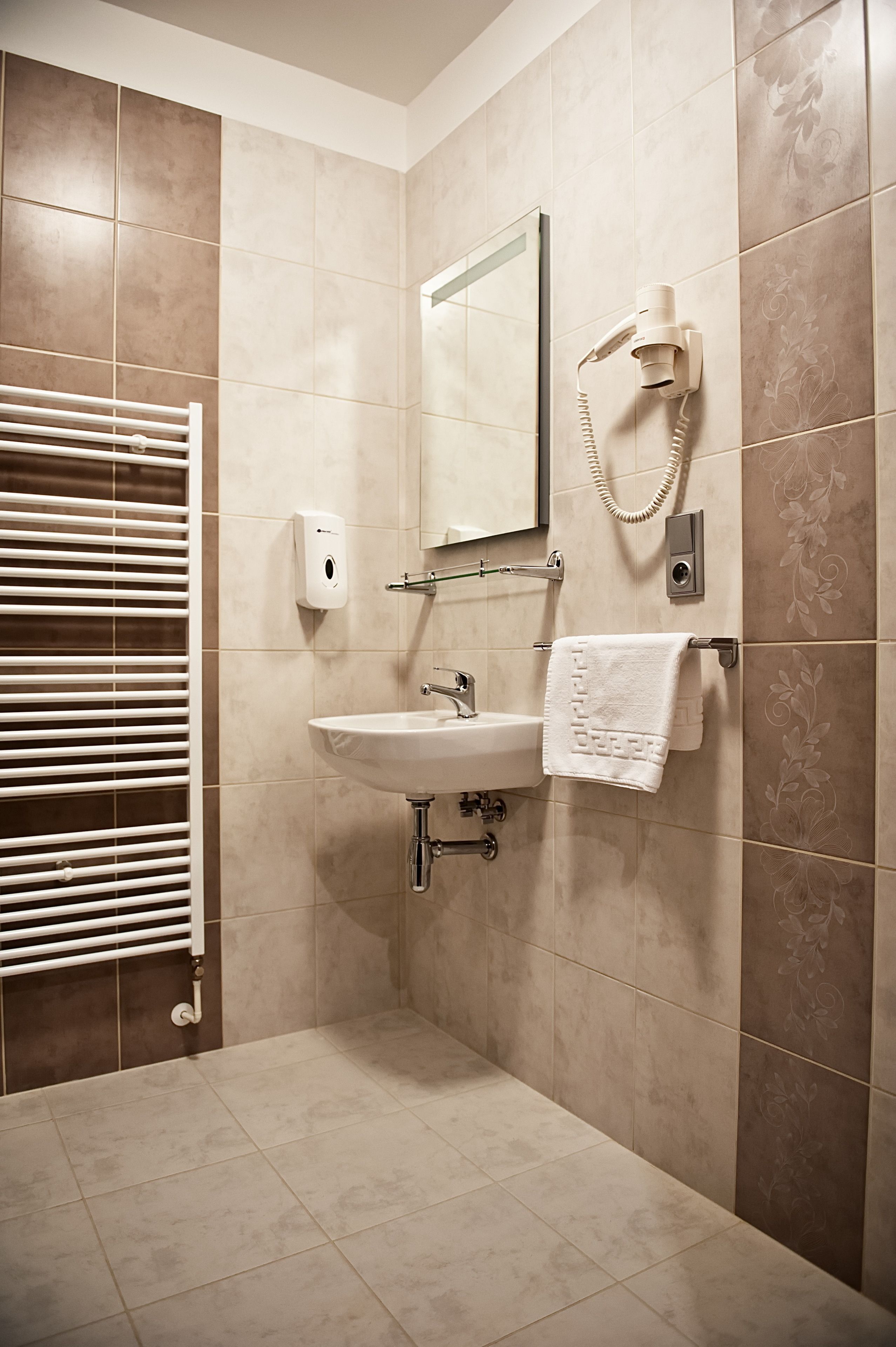 Un baño con lavamanos, toallero y secador de pelo en la pared.