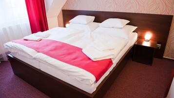 A neatly made bed with white and red bedding, a wooden headboard, and bedside lamps.