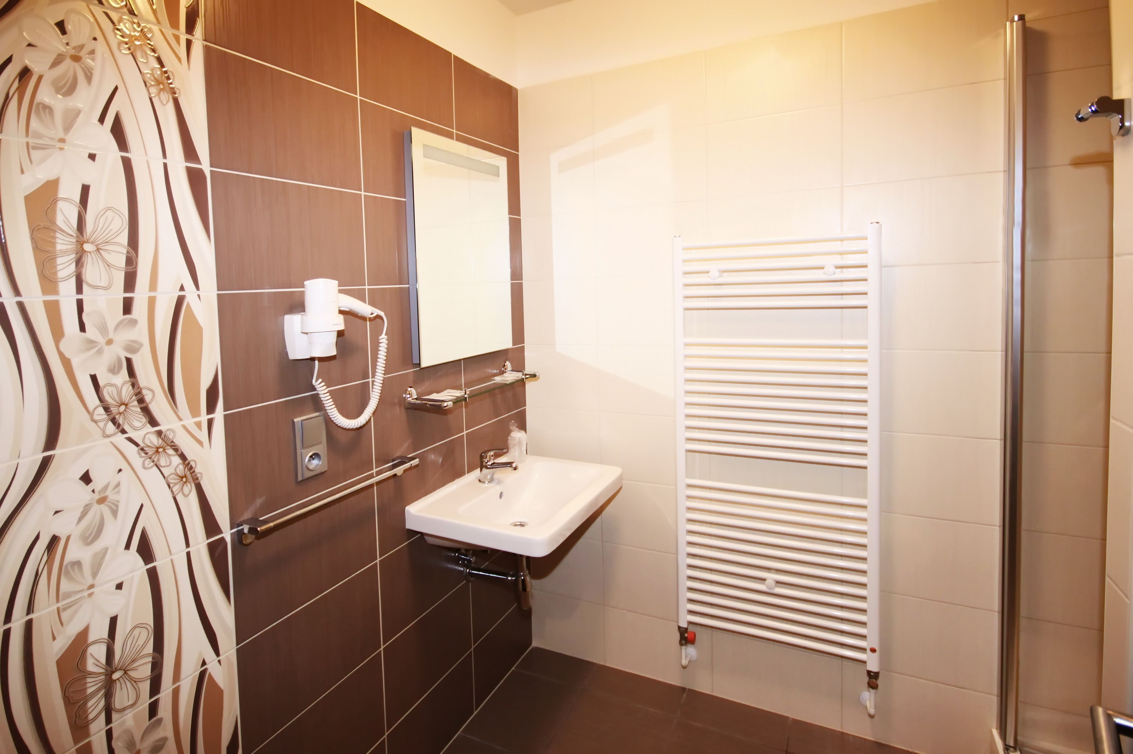 A bathroom with a white sink, a mirror, a towel rack, and a shower with a glass door.
