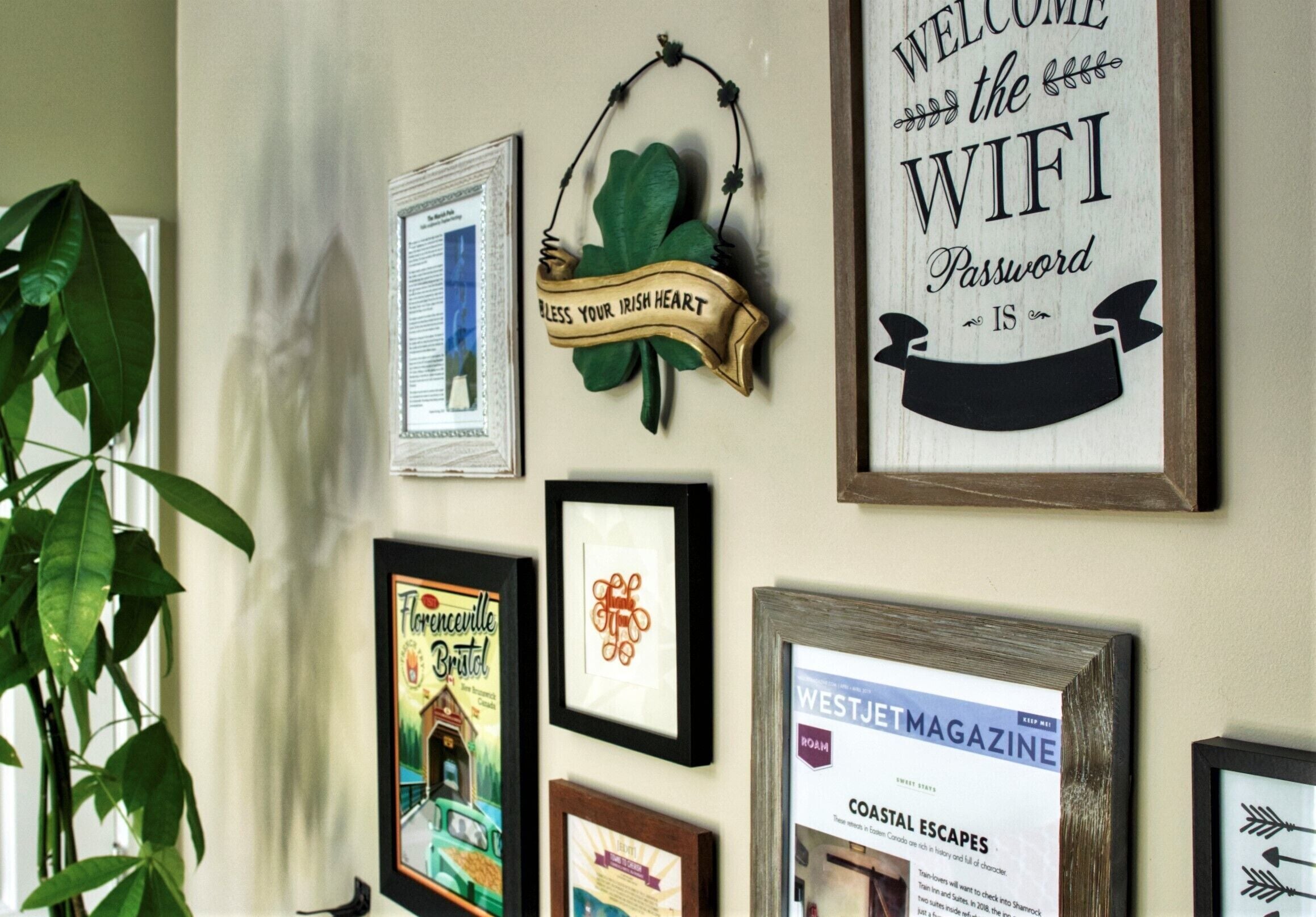 A wall with various framed items, including a sign that says "WELCOME the WIFI Password is" and a framed magazine cover.