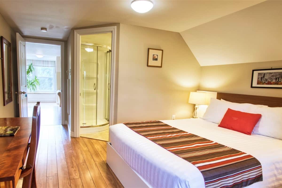 Ein Hotelzimmer mit Bett, Schreibtisch und Duschbereich.