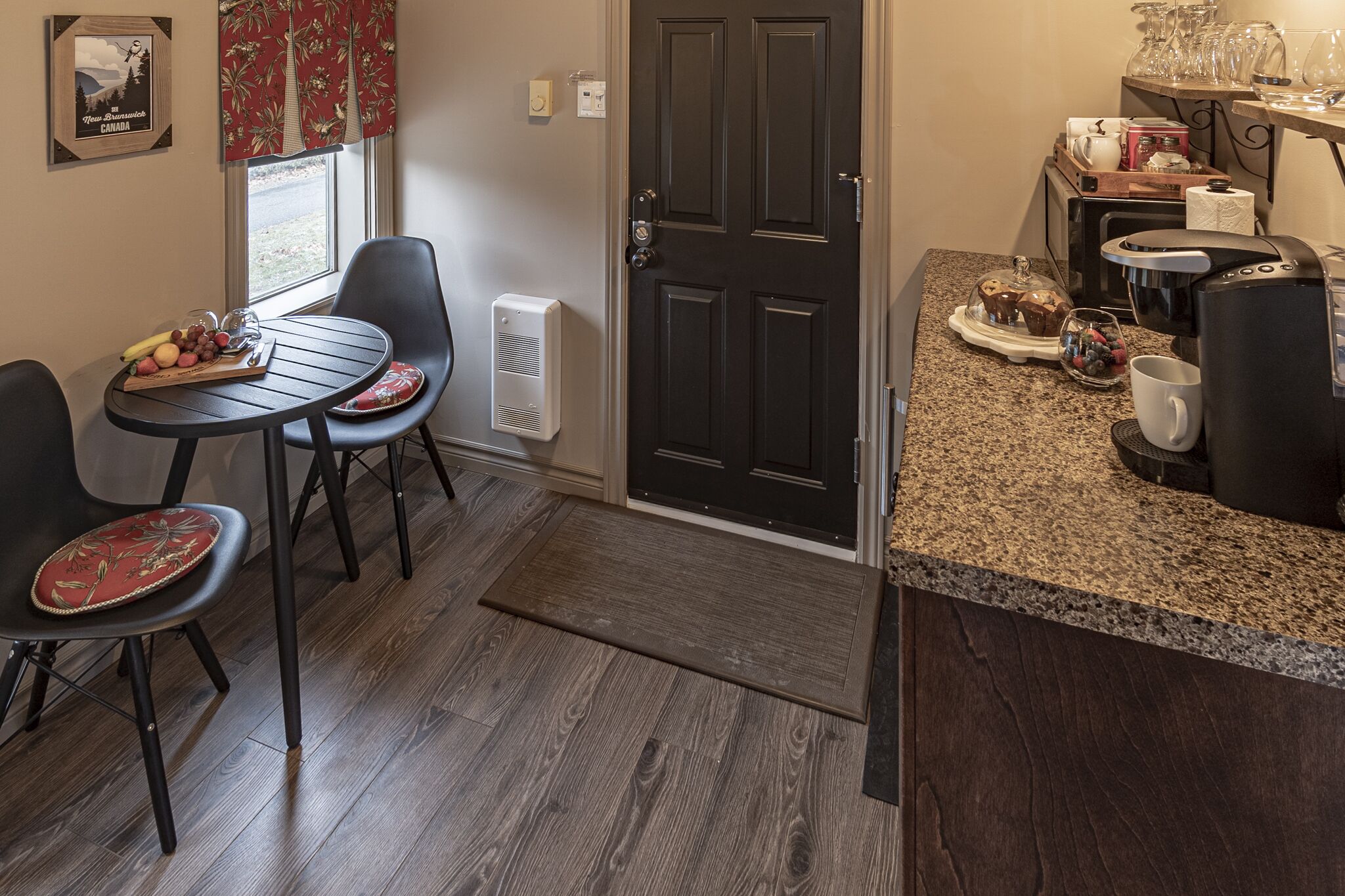 A compact kitchen with a dining area, featuring a small table with chairs, a coffee maker, and a microwave.