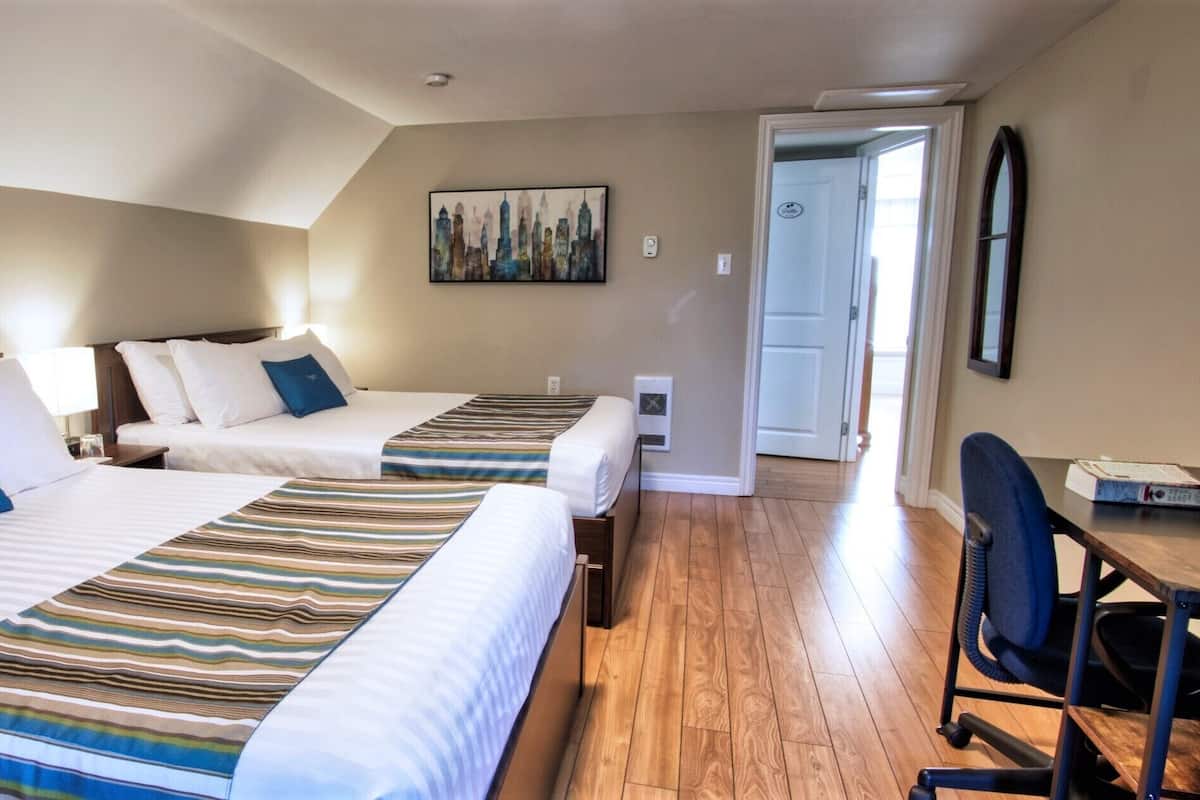 Ein Hotelzimmer mit zwei Betten, einem Schreibtisch und einem Stuhl.