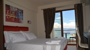 A hotel room with a bed, a desk, and a view of the sea. - Lydia Apartments (Istiaia-Aidipsos)