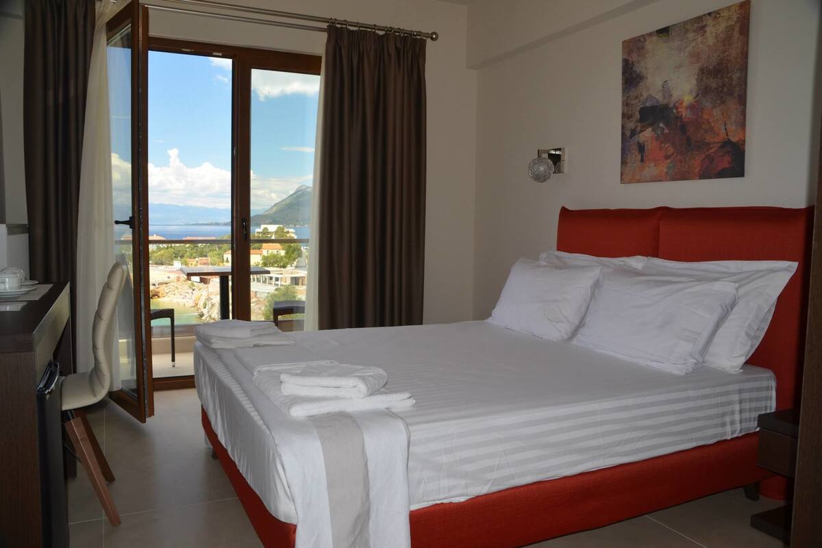 A hotel room with a bed, a desk, and a view of a mountainous landscape.