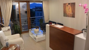 A modern reception area with a wooden desk, a glass coffee table, and a painting on the wall. - Lydia Apartments (Istiaia-Aidipsos)