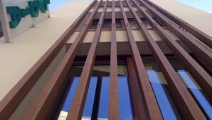A modern building with a prominent green sign and a series of horizontal beams. - Lydia Apartments (Istiaia-Aidipsos)