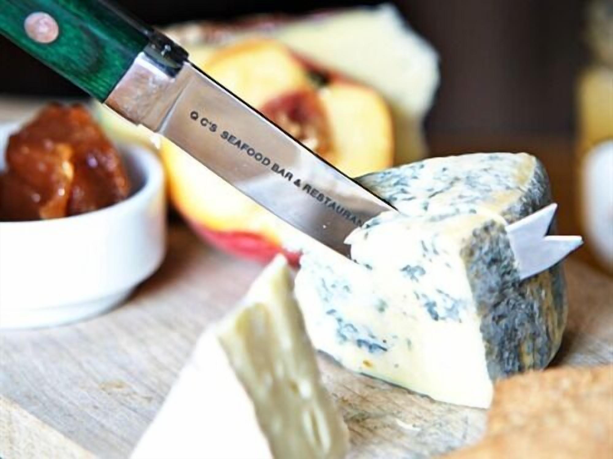 Una tabla de quesos con diferentes tipos de queso y un cuchillo.