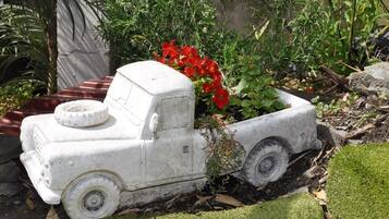 Een tuin met een witte speelgoedvrachtwagen en rode bloemen.