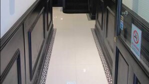 A hallway with a black staircase, white walls, and a patterned floor. - Goodwood Hotel (London)