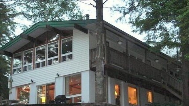 A two-story building with a stone staircase leading up to a wooden deck.