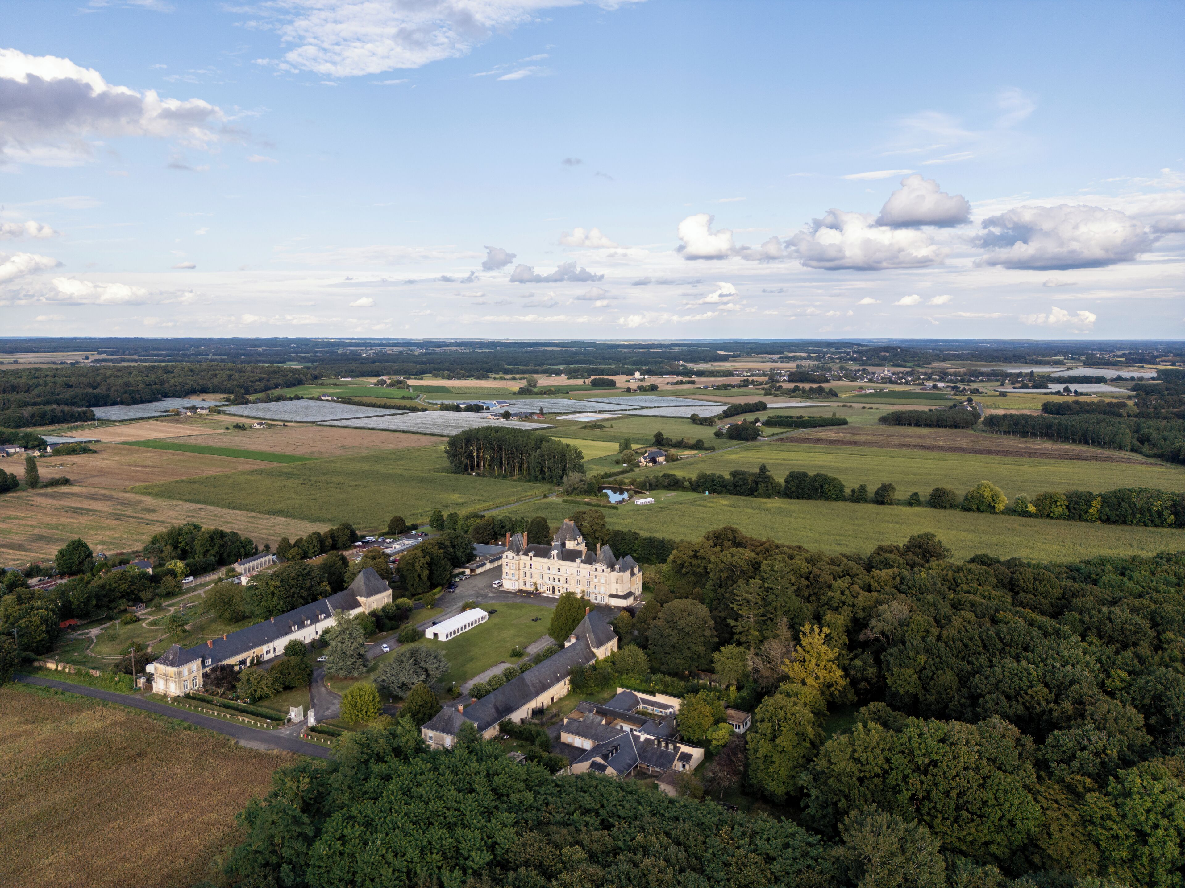Un vaste domaine comprenant plusieurs bâtiments, de vastes prairies verdoyantes et une rivière en arrière-plan.