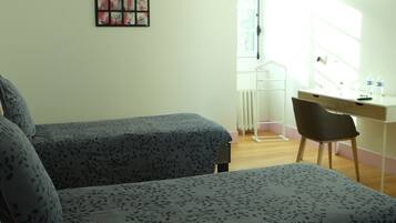 Un dormitorio con dos camas, un escritorio, una silla y un televisor montado en la pared.