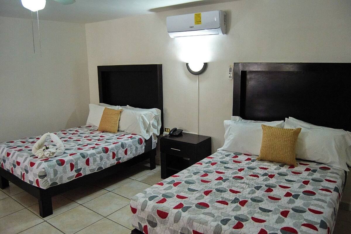 Two beds with matching headboards and a bedside table with a phone.