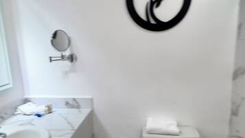 Un baño con lavamanos de mármol, inodoro y espejo montado en la pared.