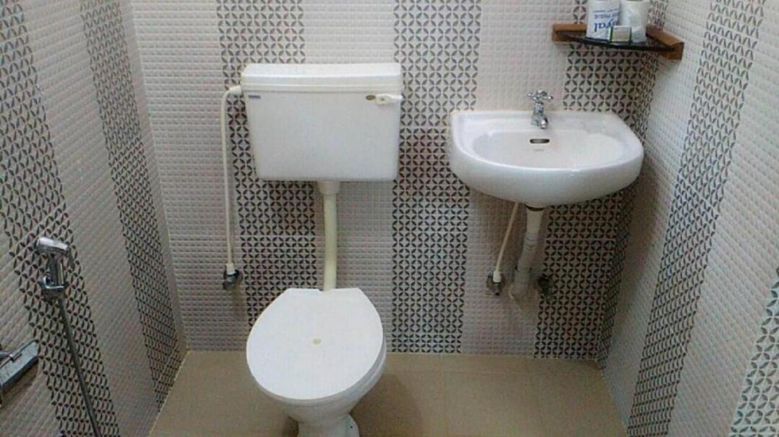 A small bathroom with a toilet, sink, and patterned walls.
