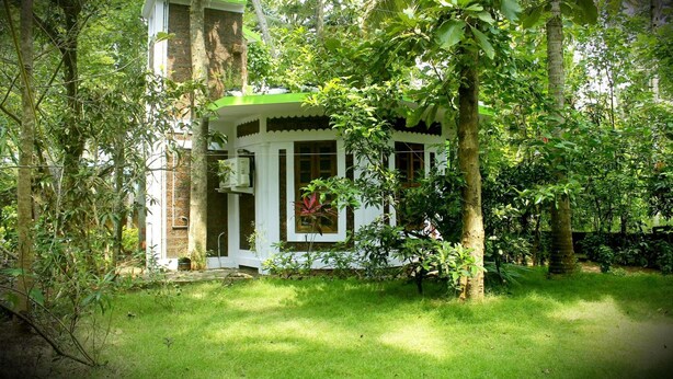 A traditional house with a green roof, surrounded by lush greenery and trees. - Jickys Nest (Varkala)