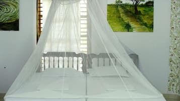 A bed with a white canopy, a window with blinds, and two paintings on the wall.