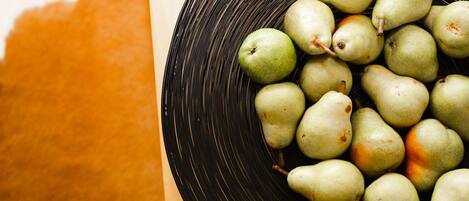 A bowl of green pears on a wooden surface.