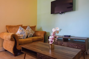 A living room with a sofa, coffee table, TV, and a decorative vase.