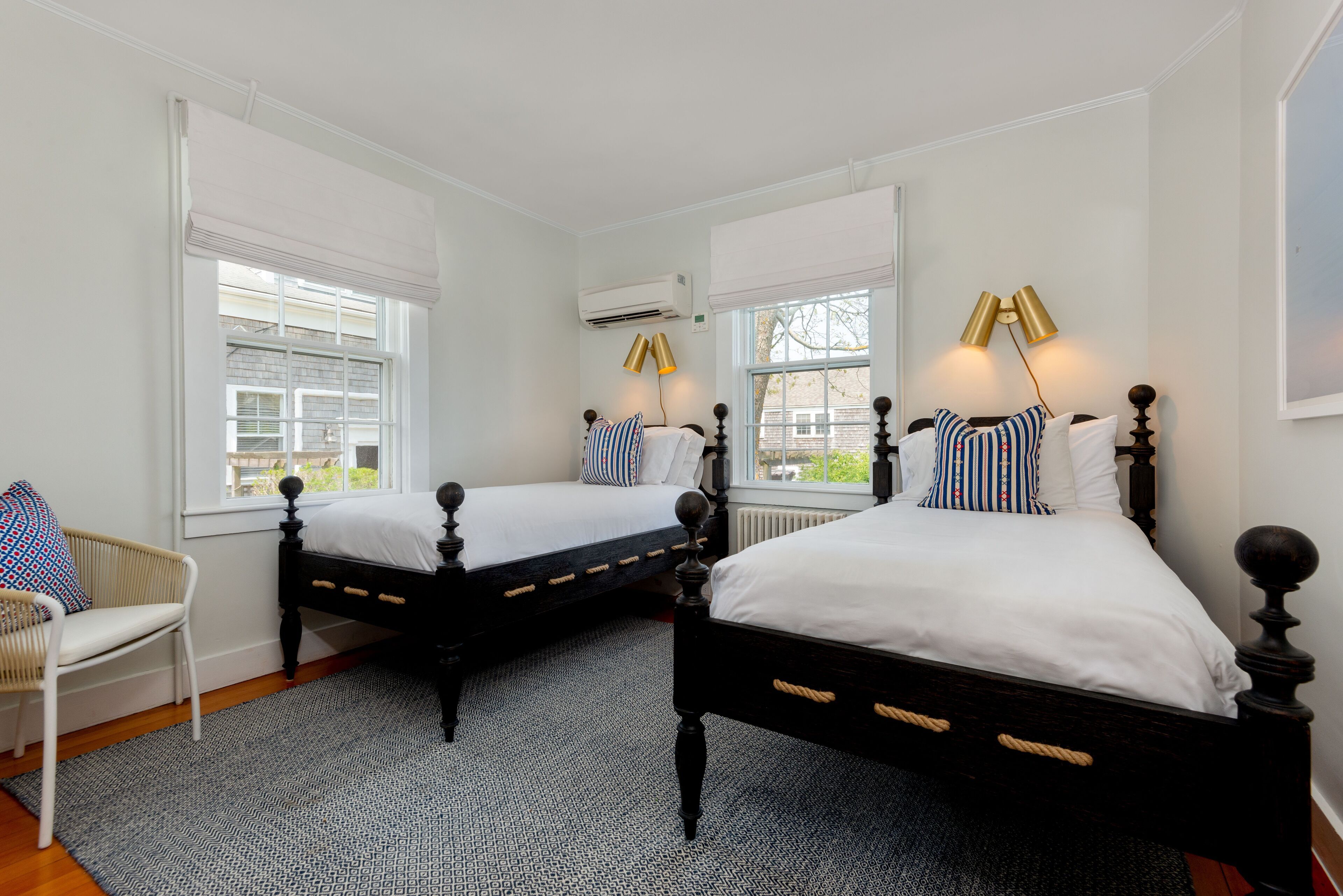 A bedroom with two beds, a chair, and a patterned rug.