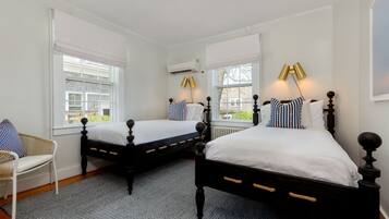 A bedroom with two beds, a chair, and a patterned rug.