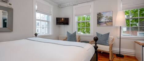A bedroom with a large bed, a television, a chair, and a lamp.