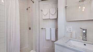 A modern bathroom with a shower, a sink, and a mirror.