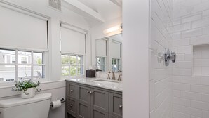 A bathroom with a toilet, sink, and mirror. - Periwinkle Inn (Nantucket)
