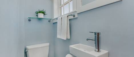 Ein Badezimmer mit Toilette, Waschbecken und einem kleinen Fenster.