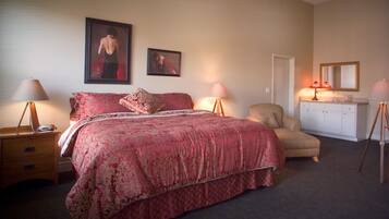 A bedroom with a large bed, two bedside tables, a chair, a desk, and a dresser.
