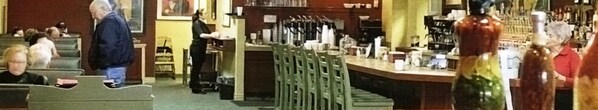 Un espace bar avec un comptoir, des chaises et une personne debout.