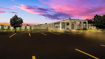 A building with a row of arched windows and a parking lot.