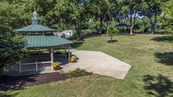 A gazebo with a green roof and a small porch, surrounded by a grassy area with trees. - Red Roof Inn & Conference Center Chicago - Aurora/ Fox Valley (North Aurora)