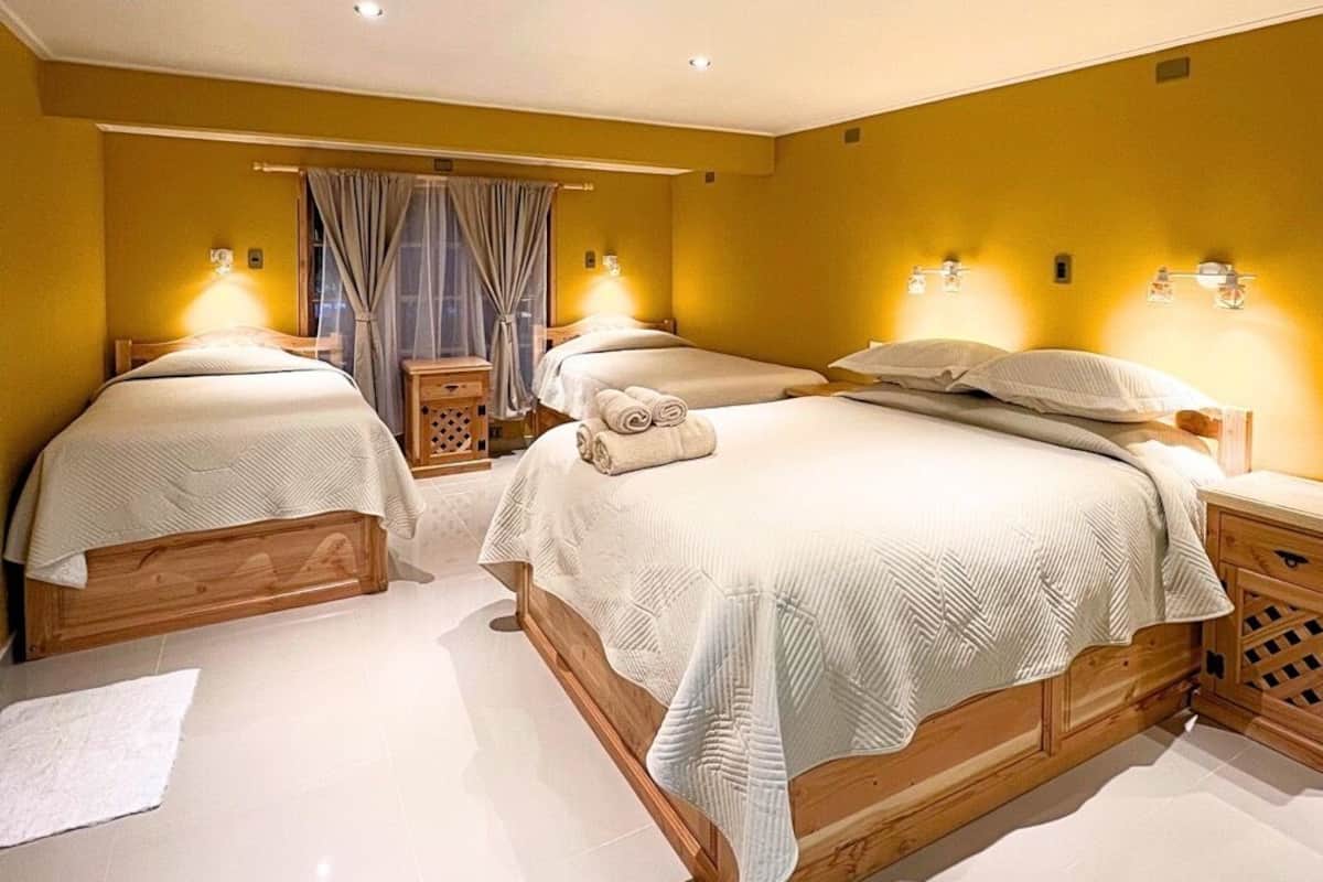 Une chambre d’hôtel avec deux lits, une tête de lit en bois, une table de chevet et une lampe fixée au mur.