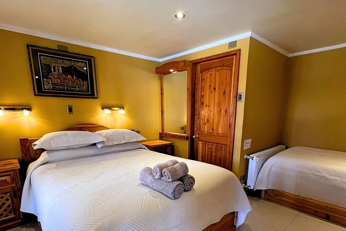 Une chambre d’hôtel avec un grand lit, une armoire en bois, une petite table et un tableau encadré au mur.