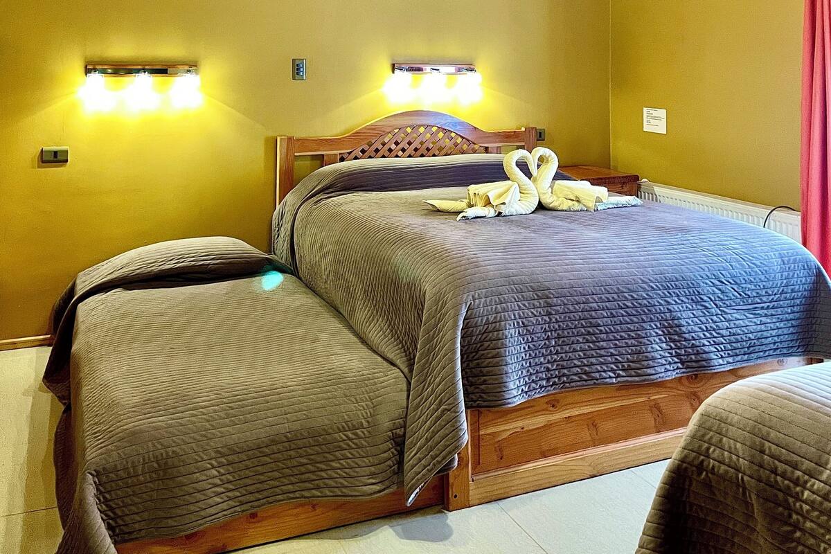 Une pièce avec un plafond en bois, un lit avec deux oreillers et une table de chevet.