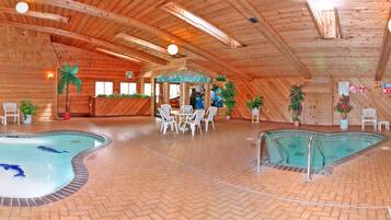 An indoor swimming pool with multiple lanes, surrounded by lounge chairs and tables.