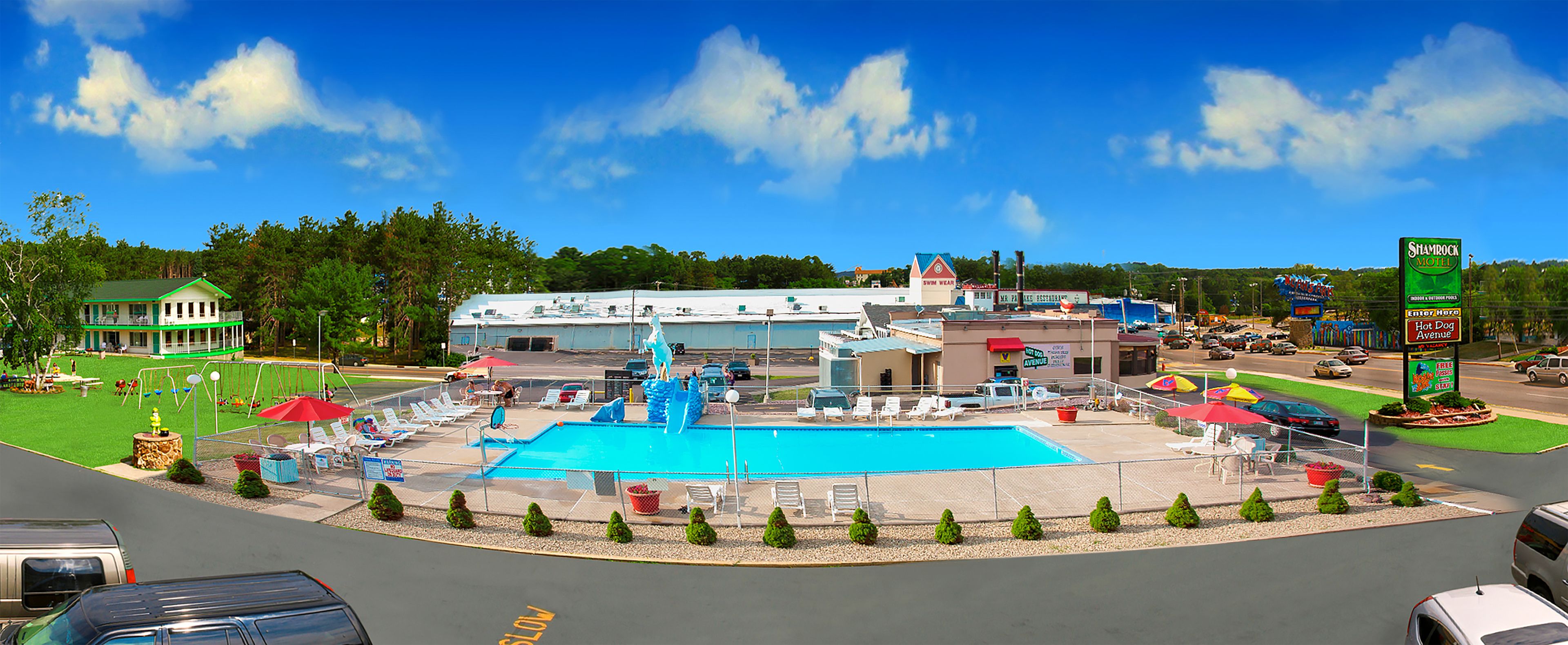 A hotel with a swimming pool, outdoor seating, and a parking lot.