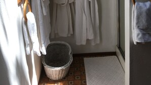 Kylpyhuoneessa on valkoisia pyyhkeitä puisiin telineisiin ripustettuna, seinällä on suuri kalanmuotoinen koriste ja lattialla punottu kori.