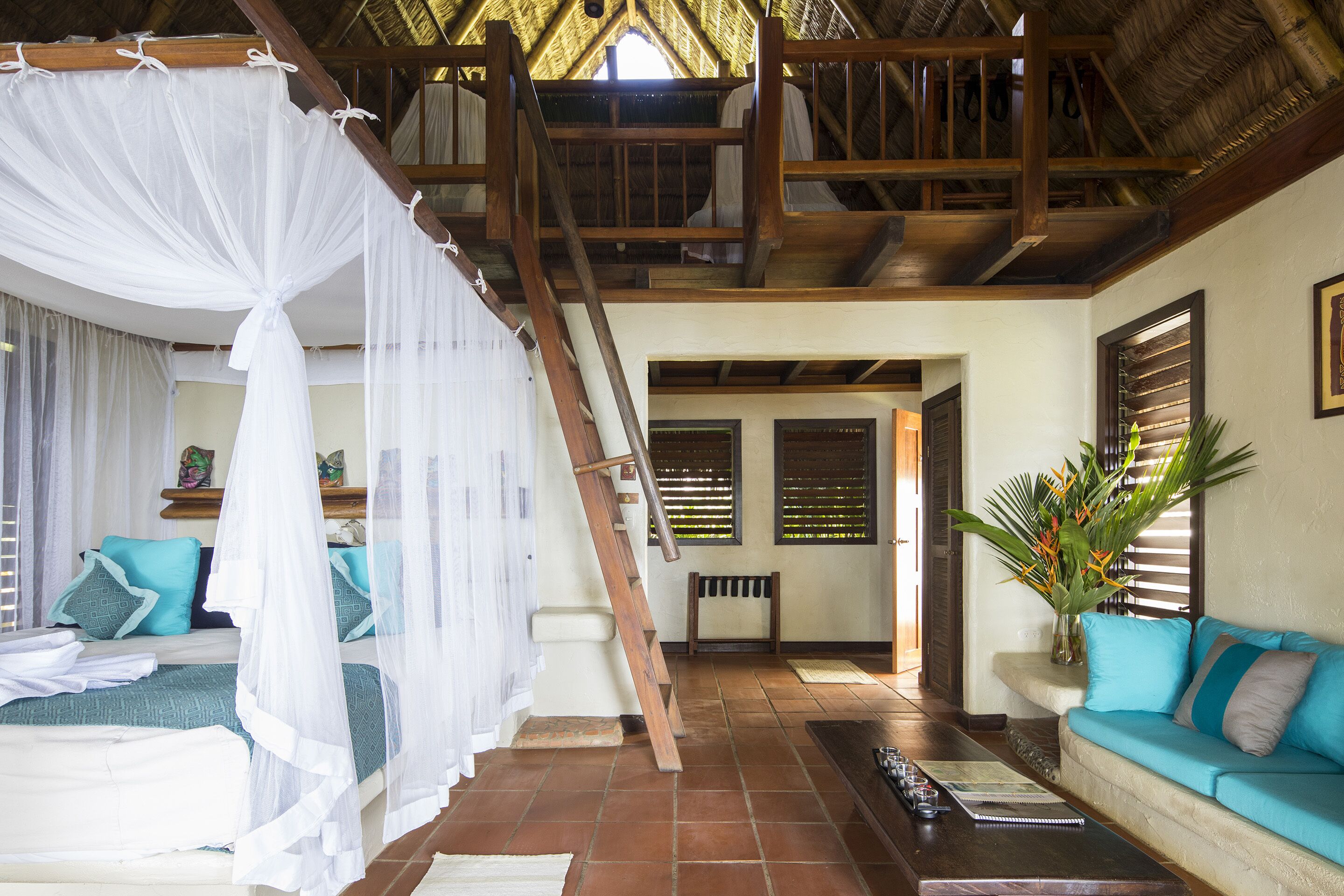 A room with a bed, a sofa, a staircase, and a view of the outside.