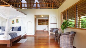 A spacious room with a high ceiling, a bed with a canopy, a wicker chair, and a view of the outdoors.