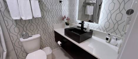 A modern bathroom with a white toilet, a black vanity with a sink, and a mirror above the vanity.