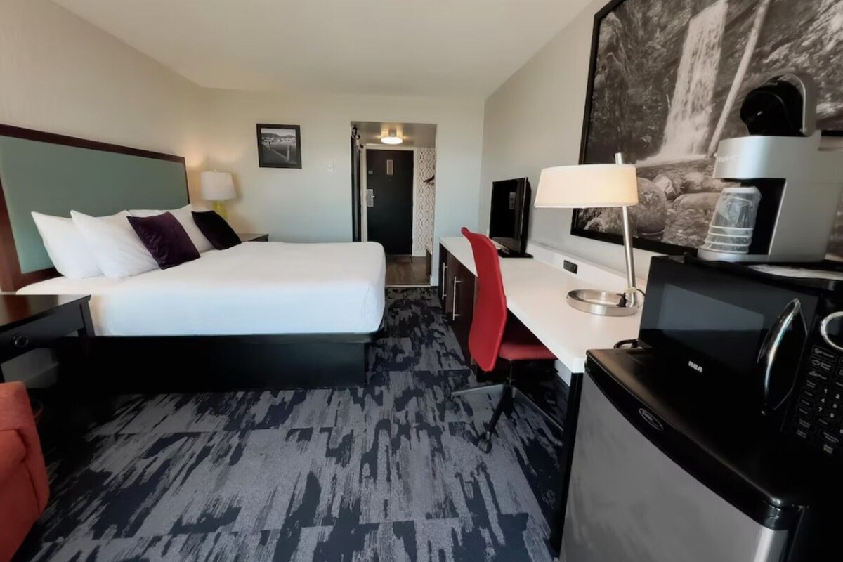 Una habitación de hotel con cama, escritorio, silla y microondas.