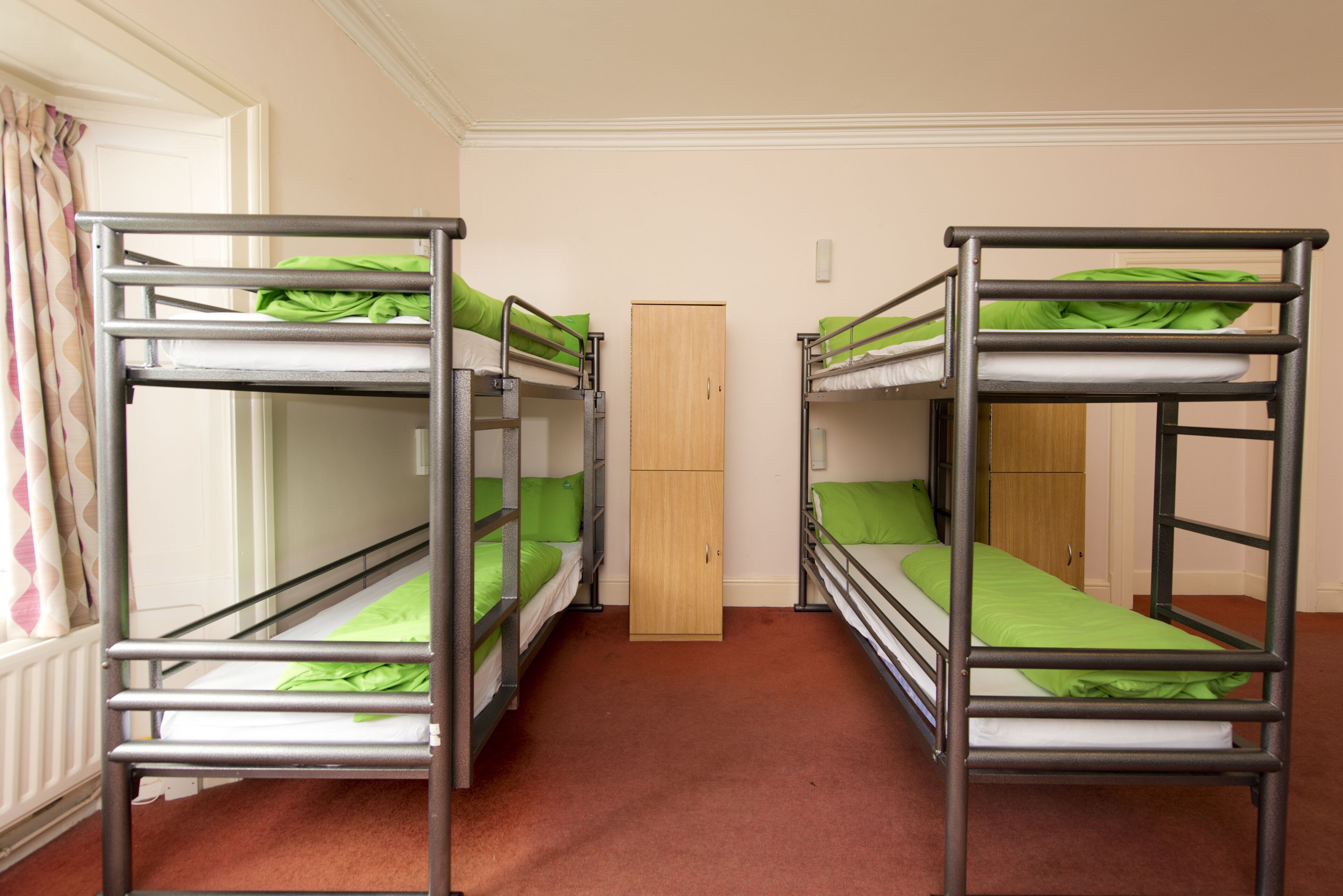 Quarto com beliches, guarda-roupa de madeira e radiador.