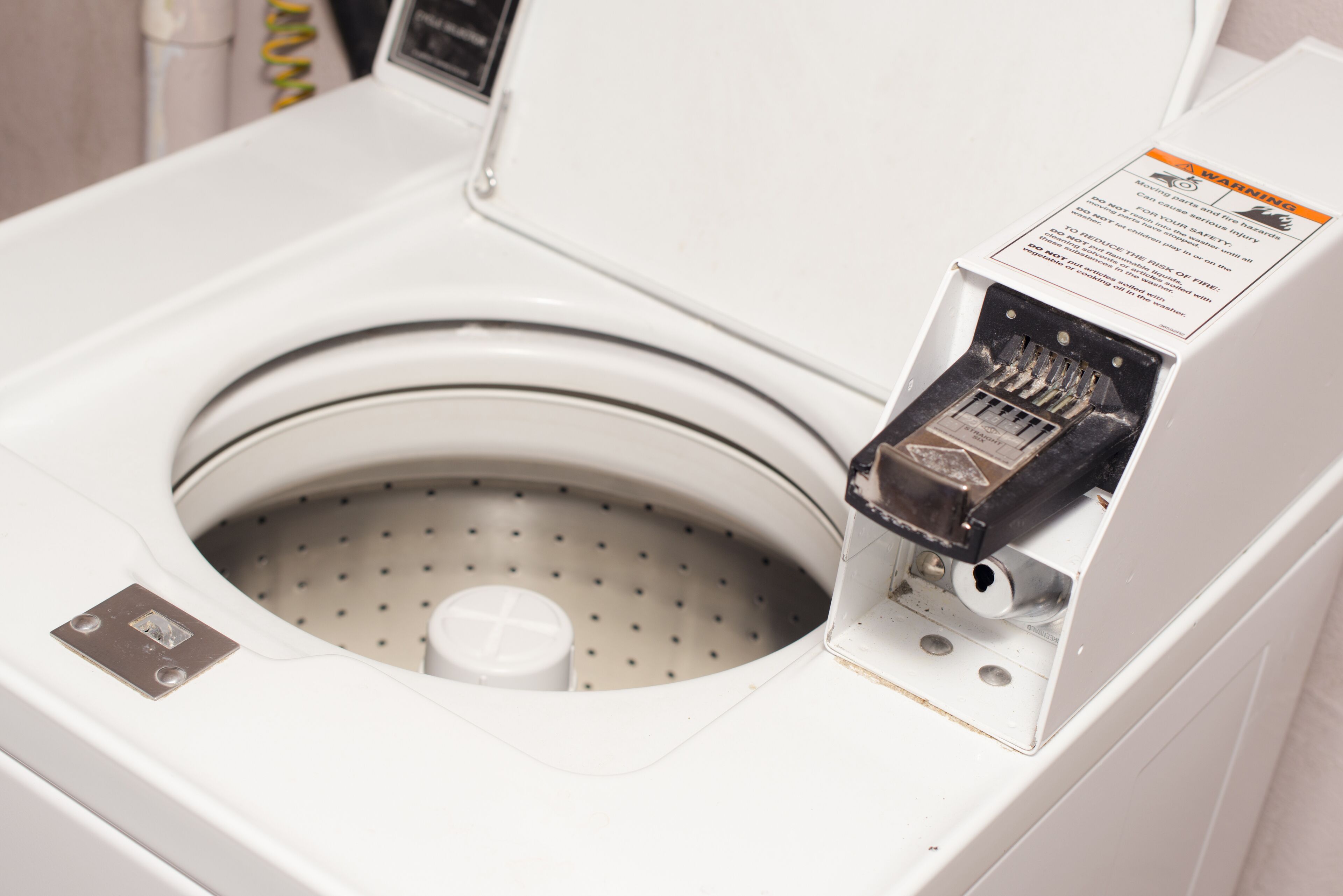 A front-loading washing machine with a front control panel and a warning label.