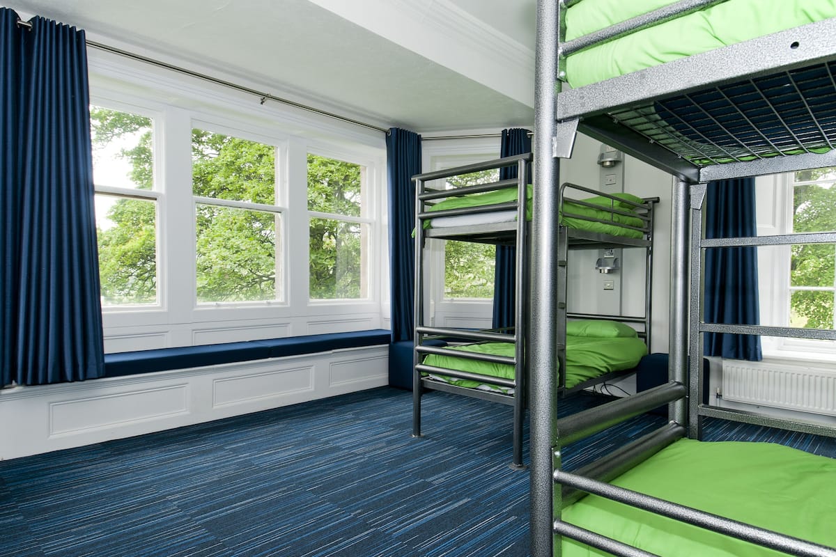 A bunk room with bunk beds, large windows, and a blue carpet.
