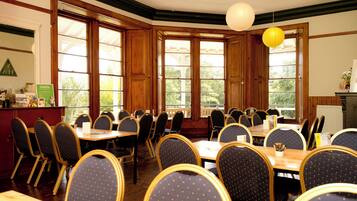 A conference room with wooden paneled walls, large windows, and a high ceiling.